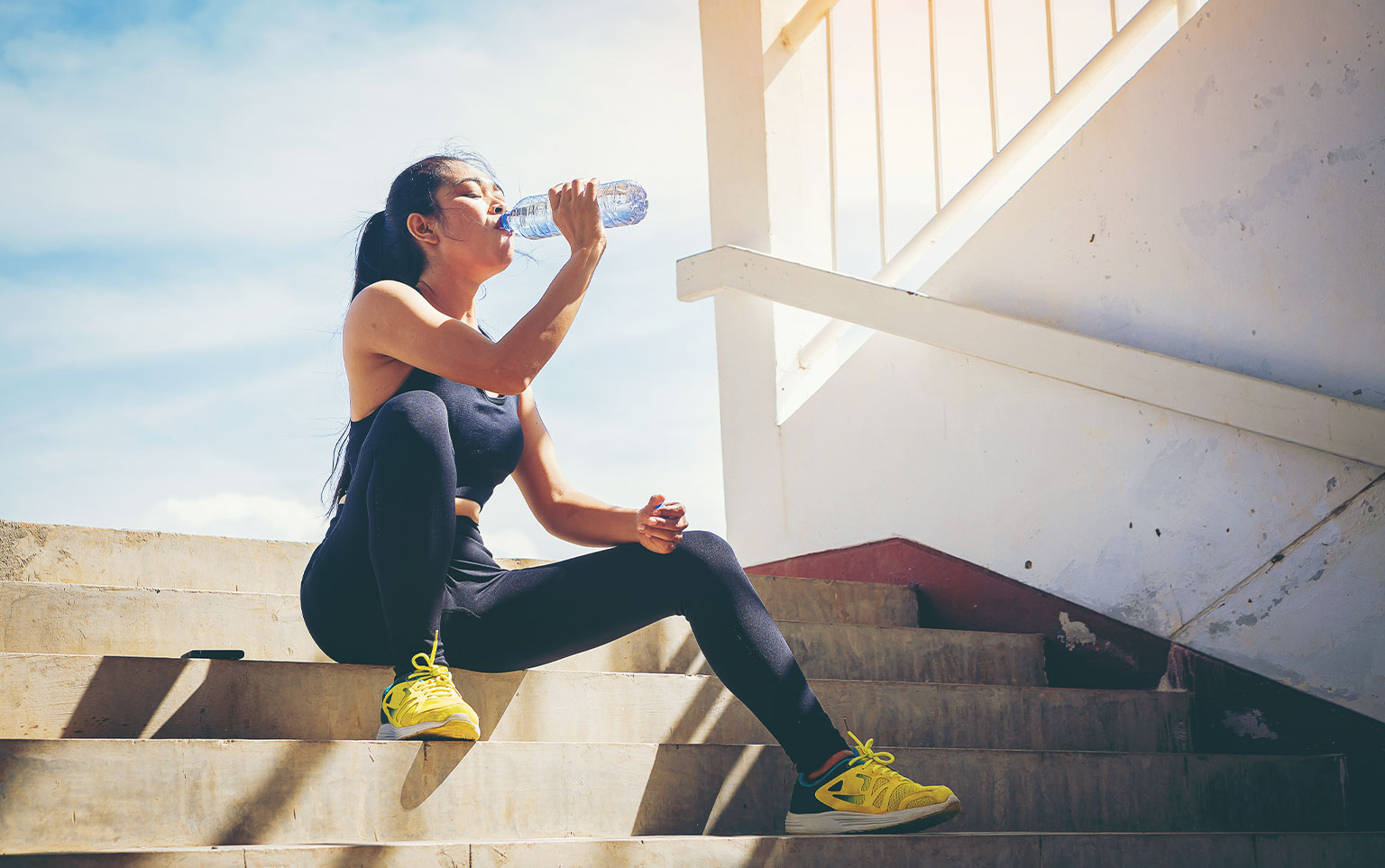 girl drinking water in athletic gear, sun safety tips