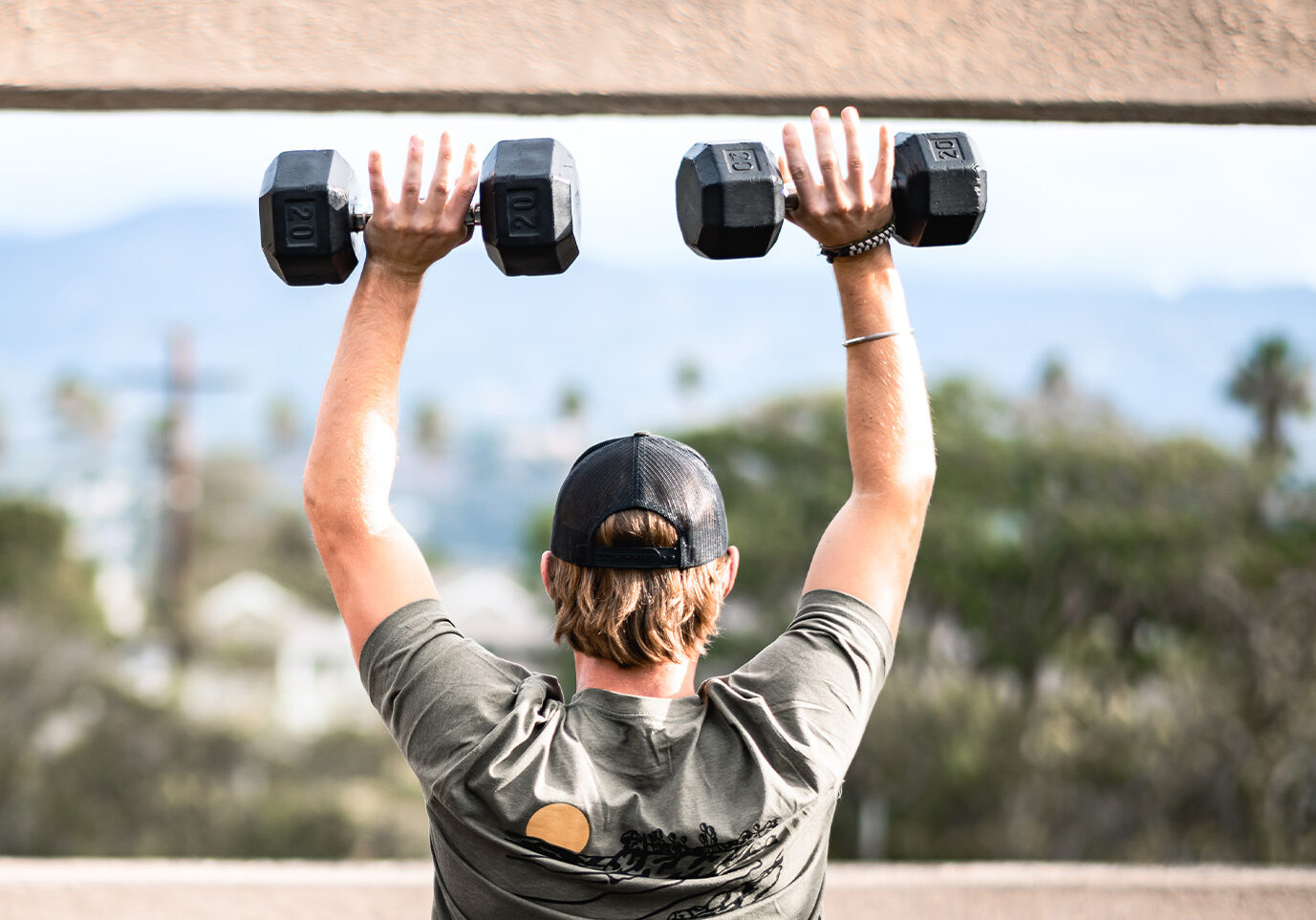 Man lifting dumbbells overhead for a blog about building muscle mass and losing fat