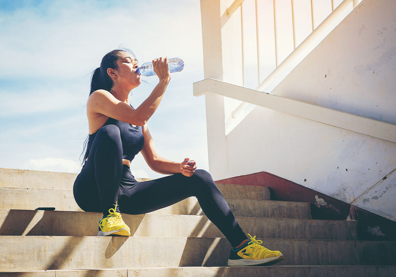 girl drinking water in athletic gear, sun safety tips