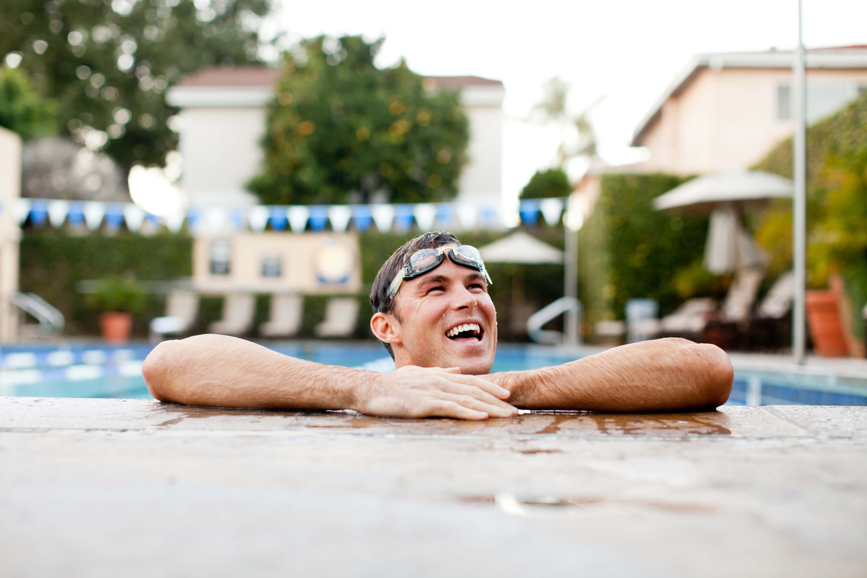 Young man leaning on pool deck while in pool