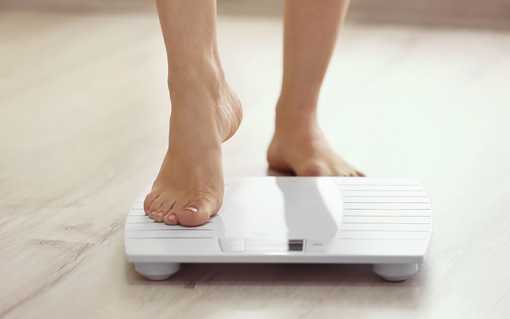 Young woman stepping onto weight scale
