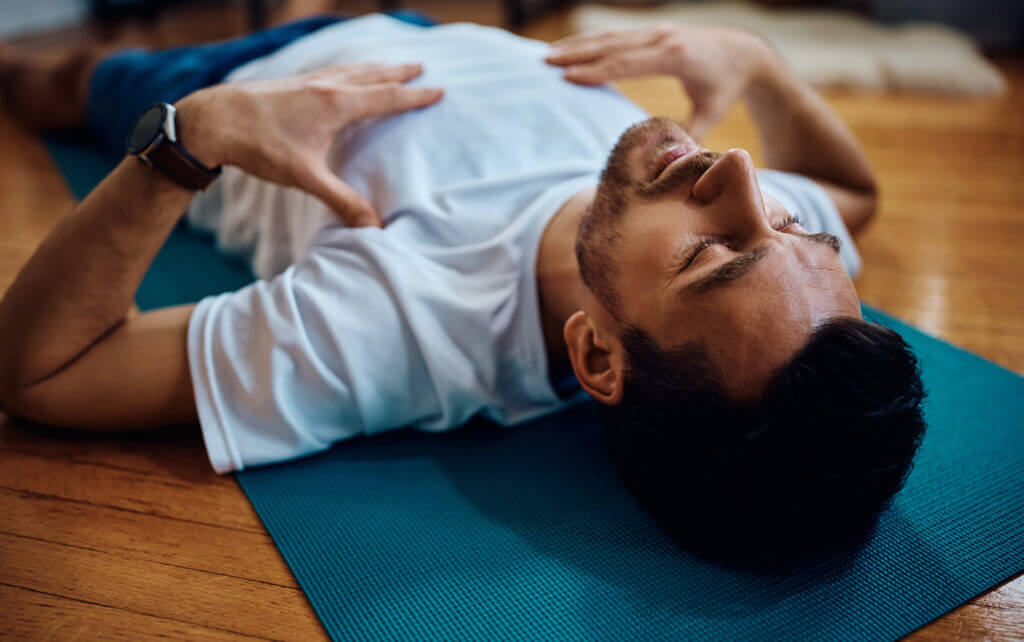 man on floor with eyes closed, using transformational breathing to meditate